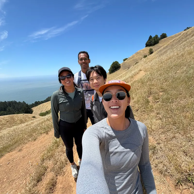 A group selfie on a grassy hillside above the ocean