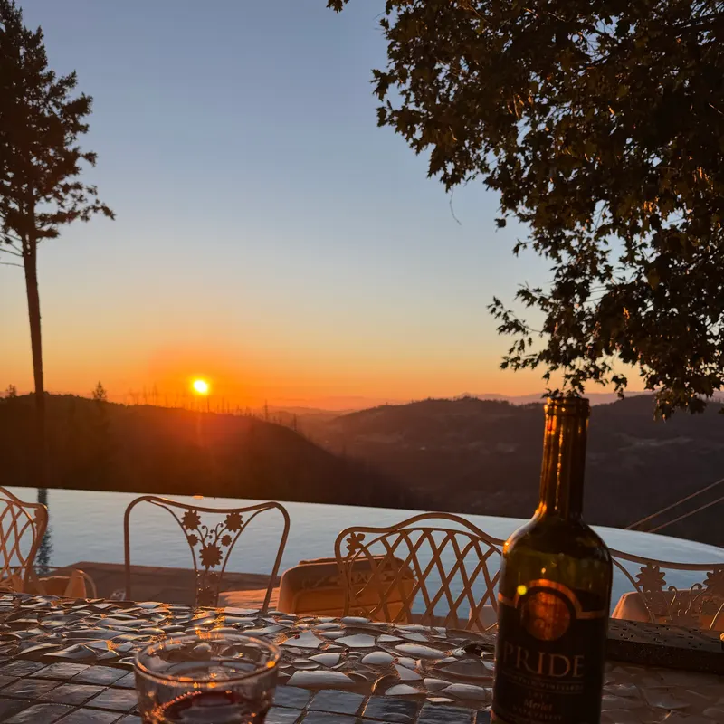 Sunset over the hills from a terrace, with a bottle of wine on the table