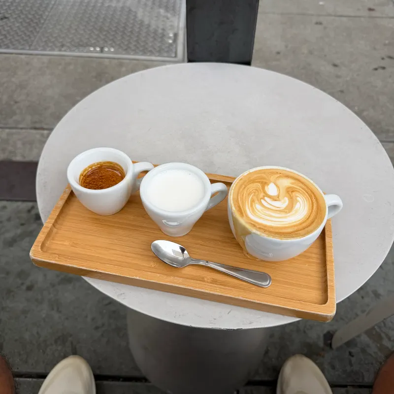 Espresso, milk and a latte on a wooden tray at a café table